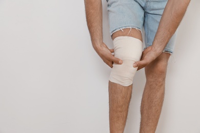 Photo of Man with bandage on his knee against light background, closeup. Space for text