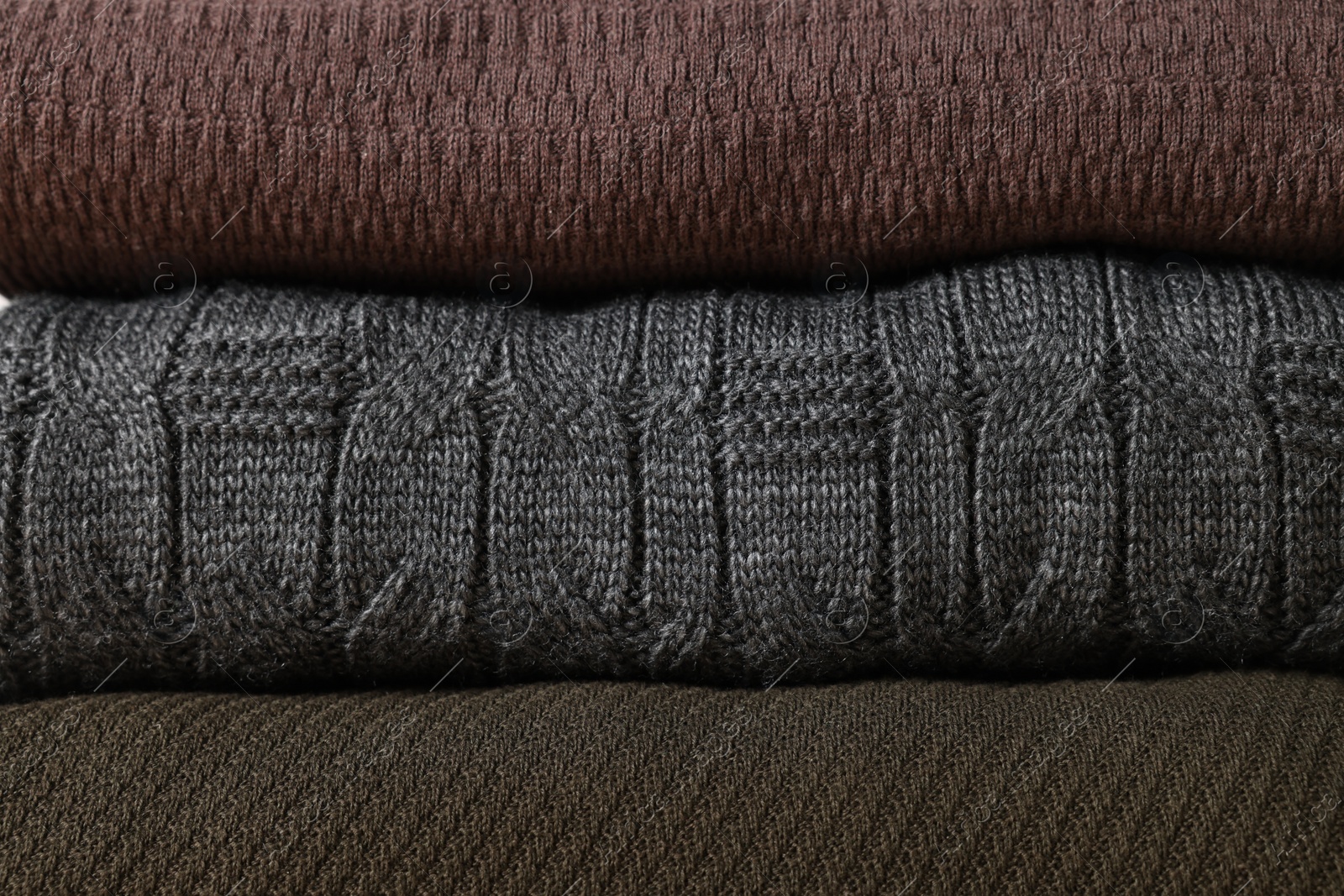 Photo of Stack of casual warm sweaters as background, closeup view