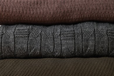 Photo of Stack of casual warm sweaters as background, closeup view