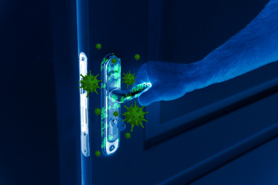 Image of Man opening door, closeup view under UV light. Avoid touching surfaces in public spaces during coronavirus outbreak