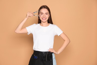 Portrait of happy hairdresser with professional scissors on beige background