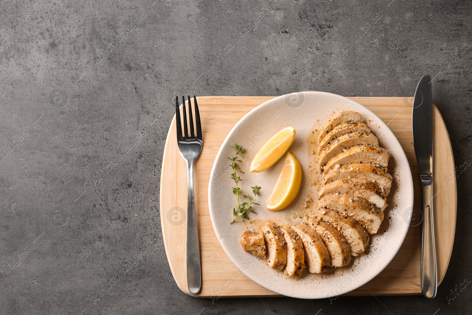 Photo of Tasty fresh lemon chicken served on grey table, top view.Space for text