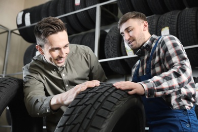 Service center consultant helping customer to choose tire in store