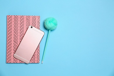 Photo of Modern smartphone, notebook and pen on light blue background, top view. Space for text