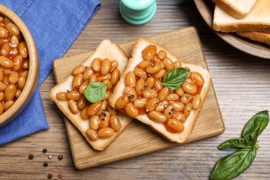 Toasts with delicious canned beans on wooden table, flat lay