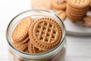 Photo of Tasty sandwich cookies with cream in jar, closeup