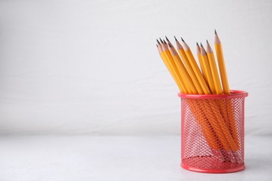 Photo of Many sharp pencils in holder on white background, space for text