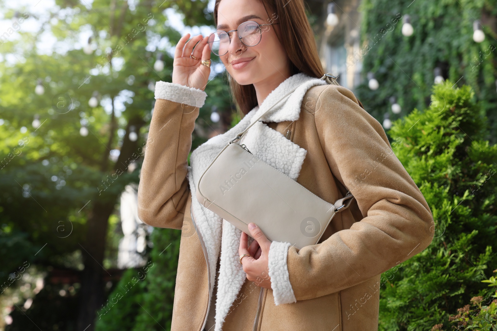 Photo of Fashionable young woman with stylish bag on city street