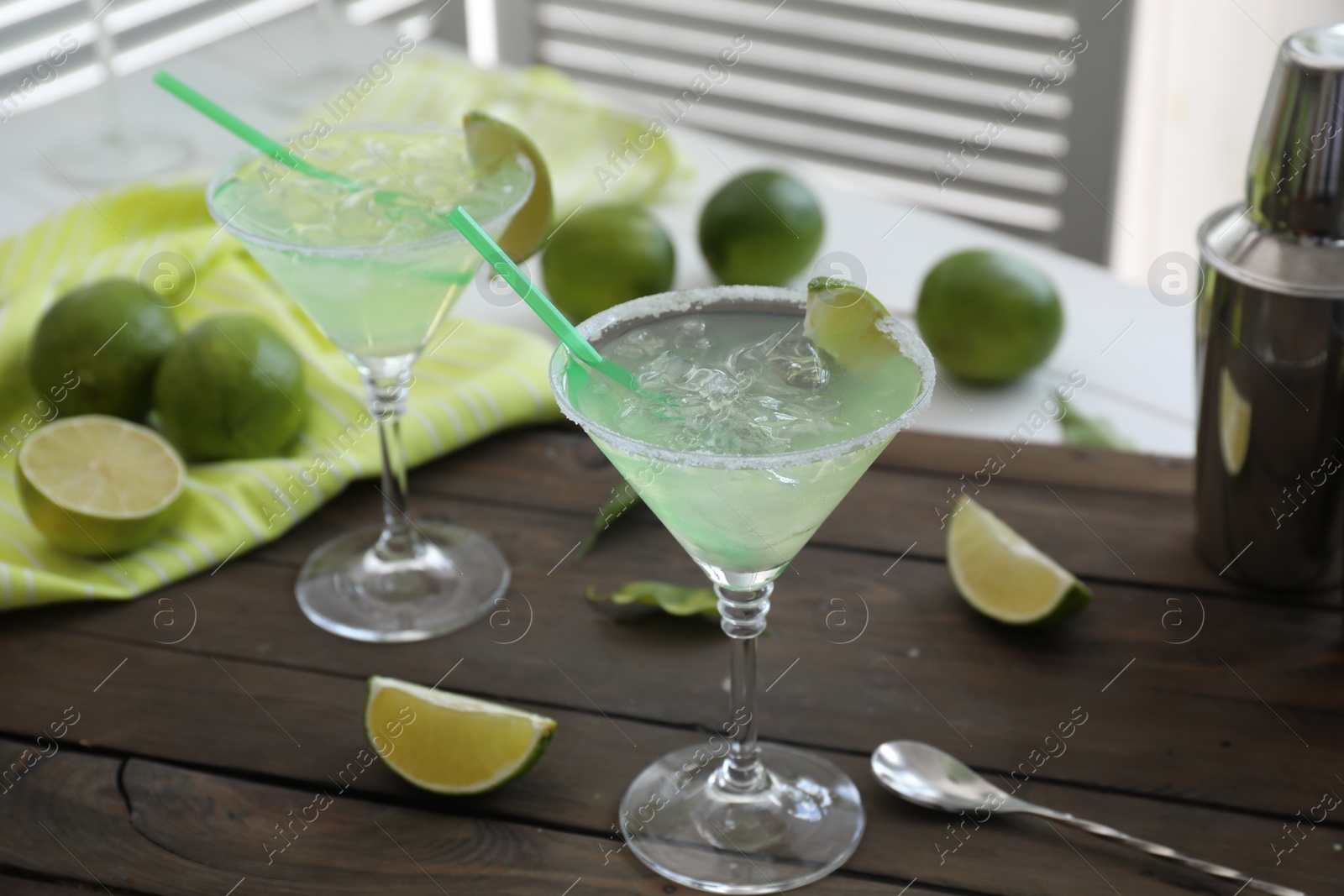 Photo of Delicious Margarita cocktail in glasses and lime on wooden table, closeup