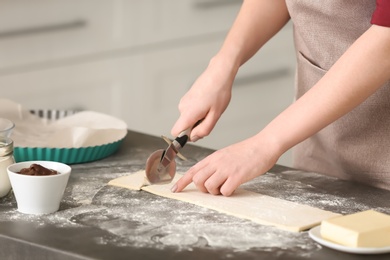 Photo of Woman preparing tasty croissants on table in kitchen, closeup