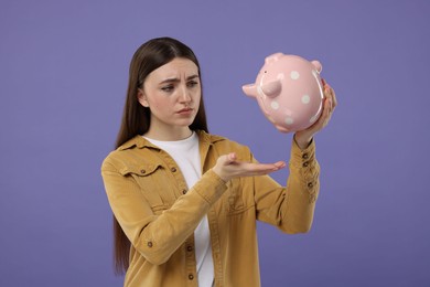 Photo of Sad woman with piggy bank on purple background