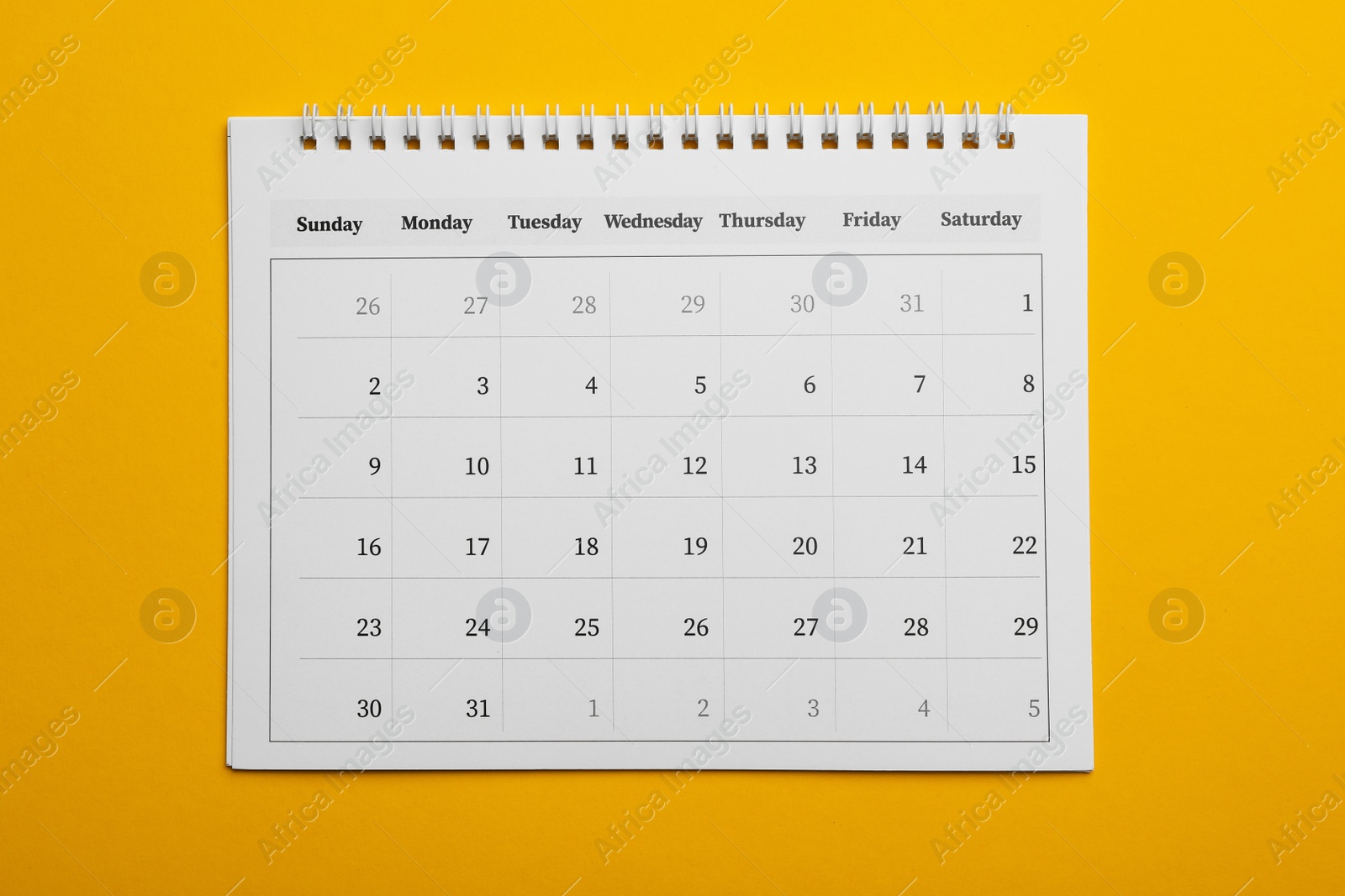 Photo of Paper calendar on yellow background, top view
