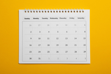 Paper calendar on yellow background, top view