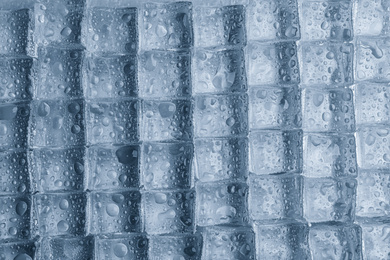 Crystal clear ice cubes with water drops as background, top view