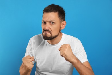 Photo of Aggressive man ready to fight on light blue background