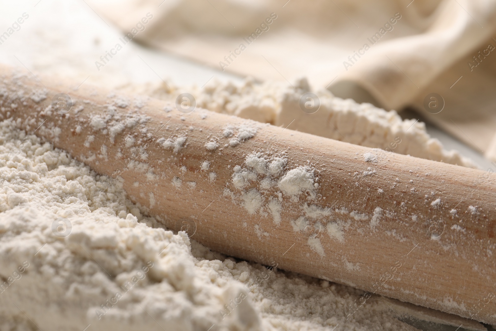 Photo of Pile of flour and rolling pin on table, closeup