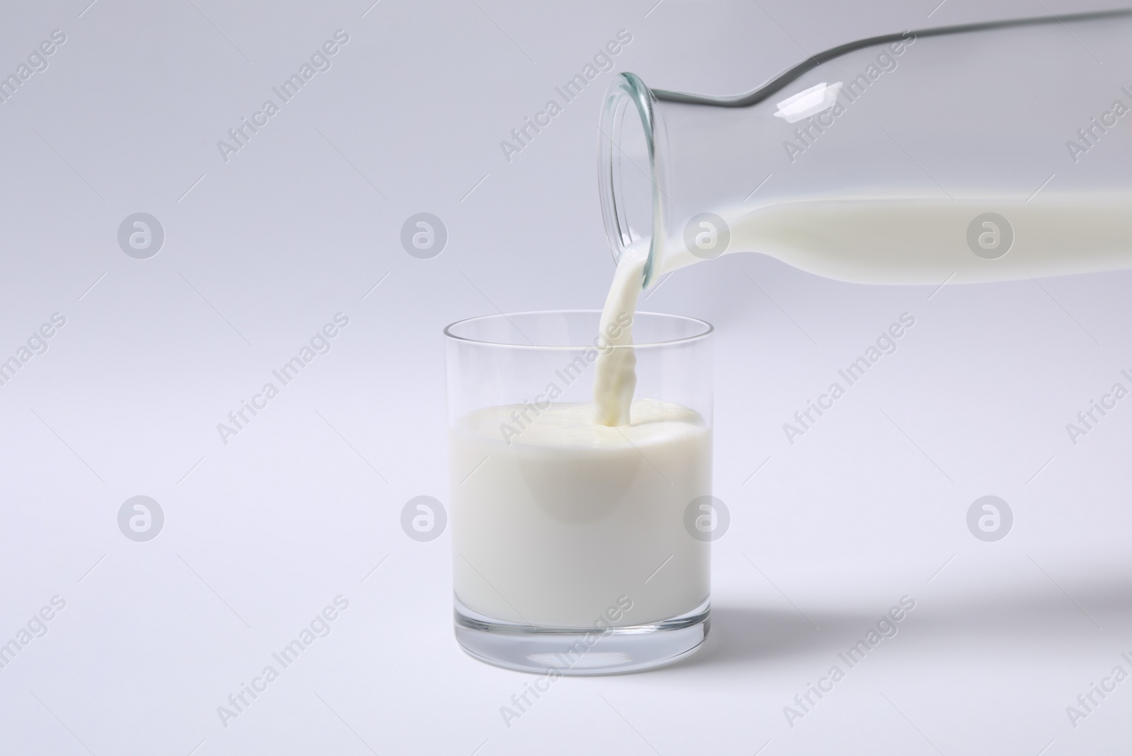 Photo of Pouring milk into glass on white background