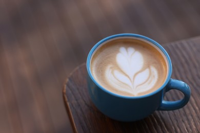 Ceramic cup of aromatic coffee with foam on wooden table. Space for text