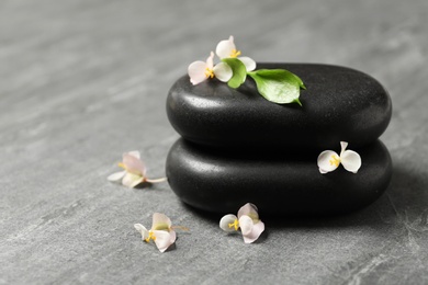 Stacked spa stones with flowers and leaves on table. Space for text