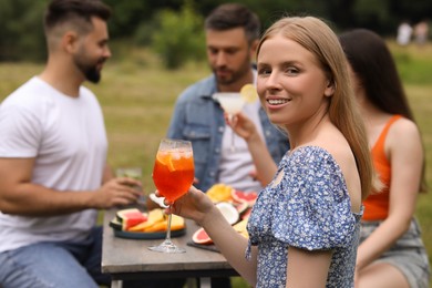 Photo of Friends having cocktail party outdoors. Happy woman with glass of drink, selective focus