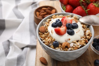 Photo of Tasty granola, yogurt and fresh berries in bowl on wooden board, closeup with space for text. Healthy breakfast