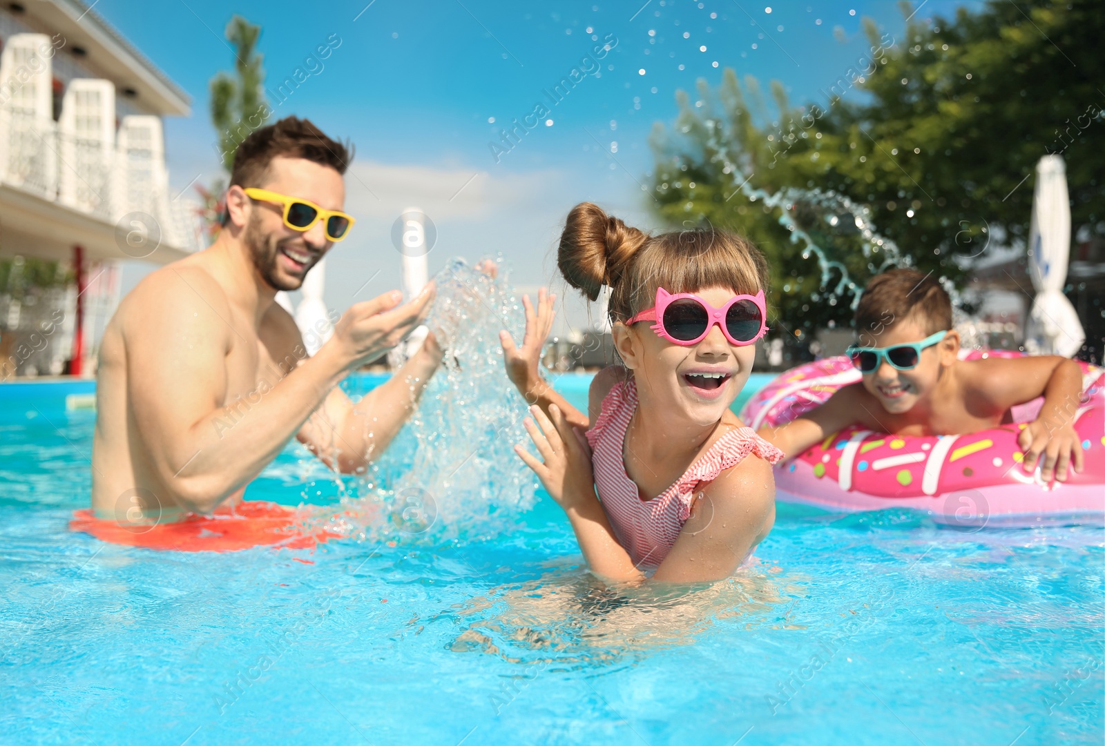 Photo of Father and children having fun in swimming pool. Family vacation