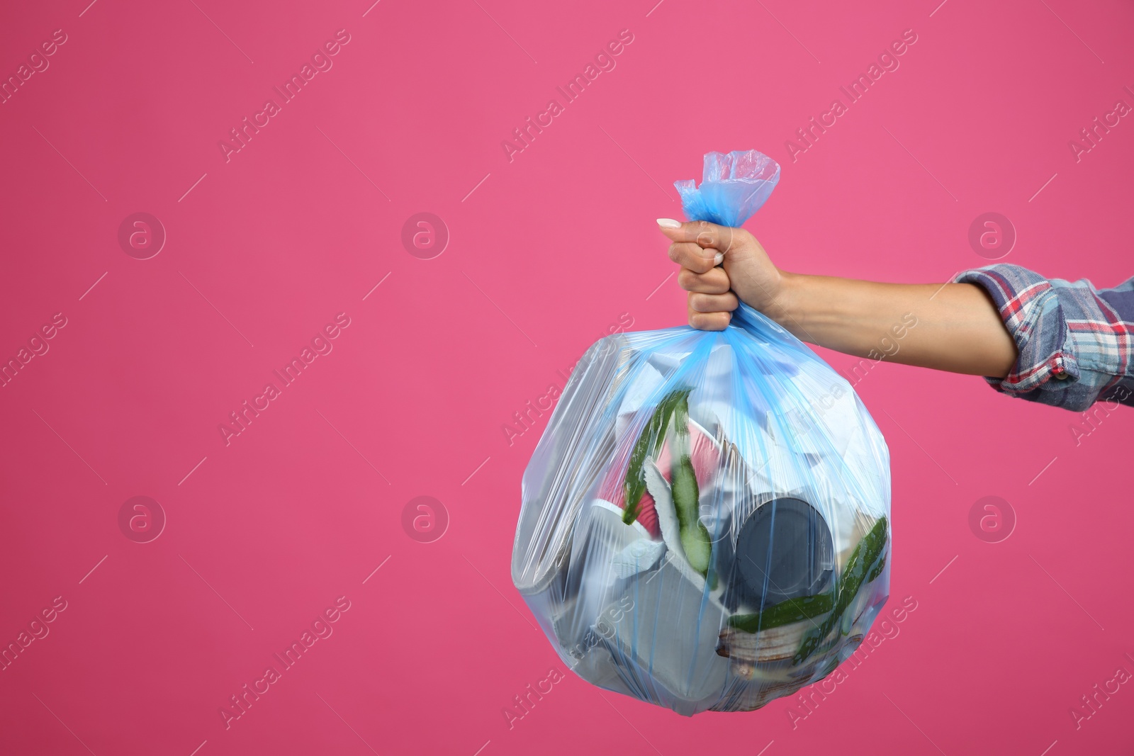 Photo of Woman holding full garbage bag on pink background, closeup. Space for text