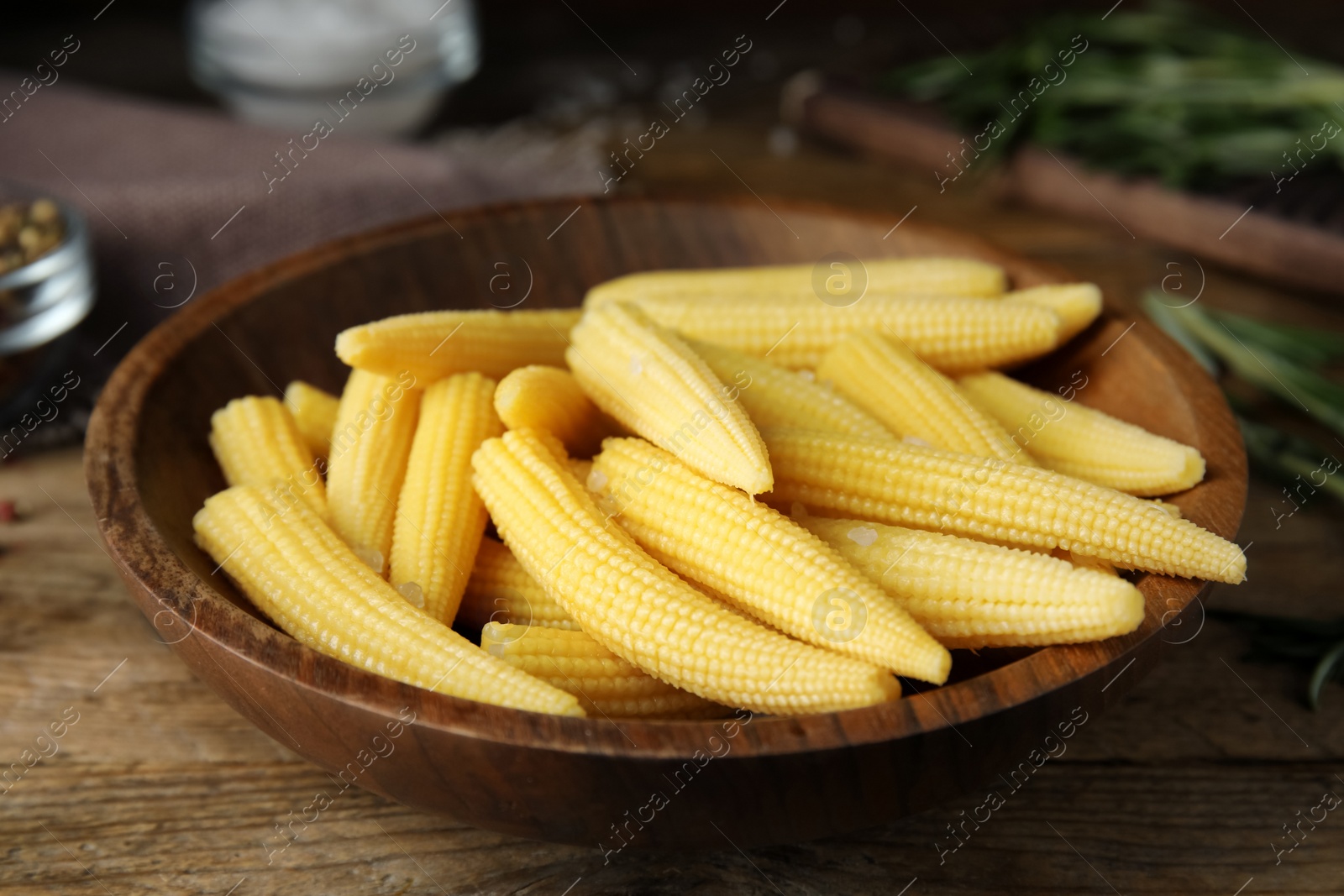 Photo of Fresh baby corn cobs on wooden table, closeup