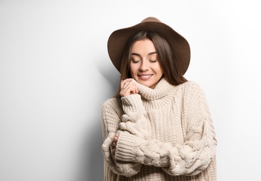 Photo of Beautiful young woman in warm sweater with hat on white background. Space for text