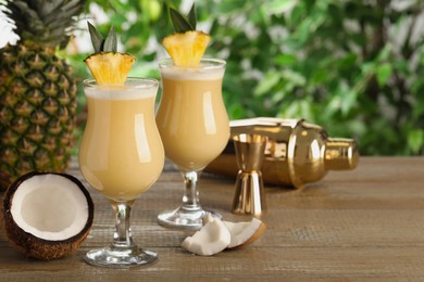 Photo of Tasty Pina Colada cocktails and ingredients on wooden table, space for text