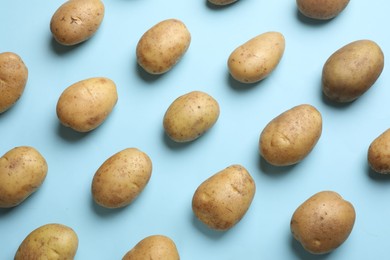 Photo of Many fresh potatoes on light blue background, flat lay