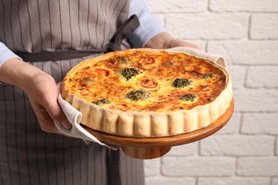 Photo of Woman holding delicious homemade vegetable quiche indoors, closeup
