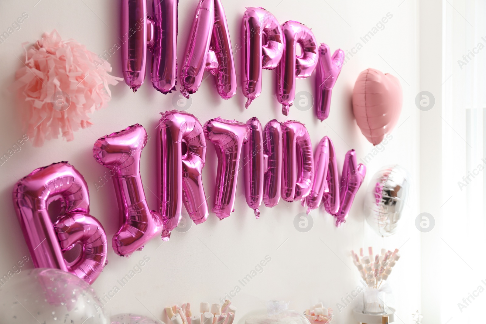 Photo of Phrase HAPPY BIRTHDAY made of pink balloon letters in decorated room