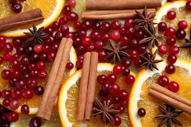 Photo of Fresh ripe cranberries, spices and orange slices as background, closeup