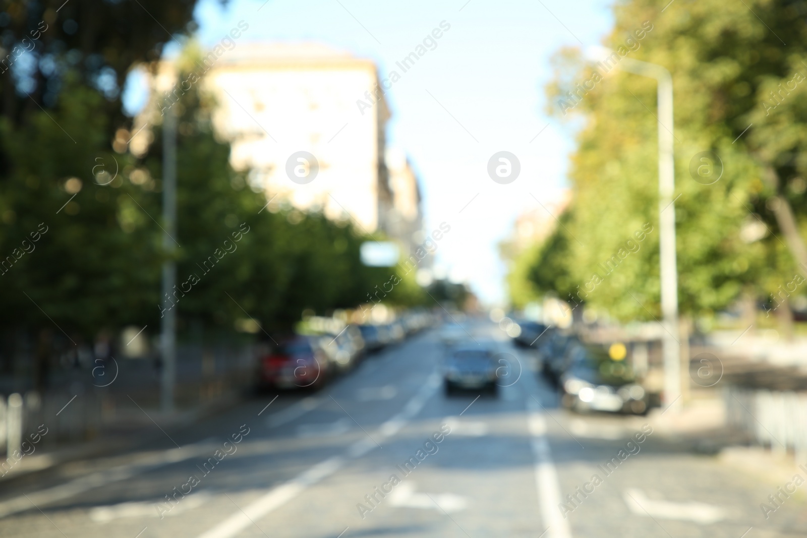 Photo of Blurred view of quiet city street with cars on road on sunny day