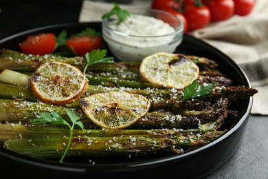 Photo of Oven baked asparagus with lemon slices served on plate, closeup