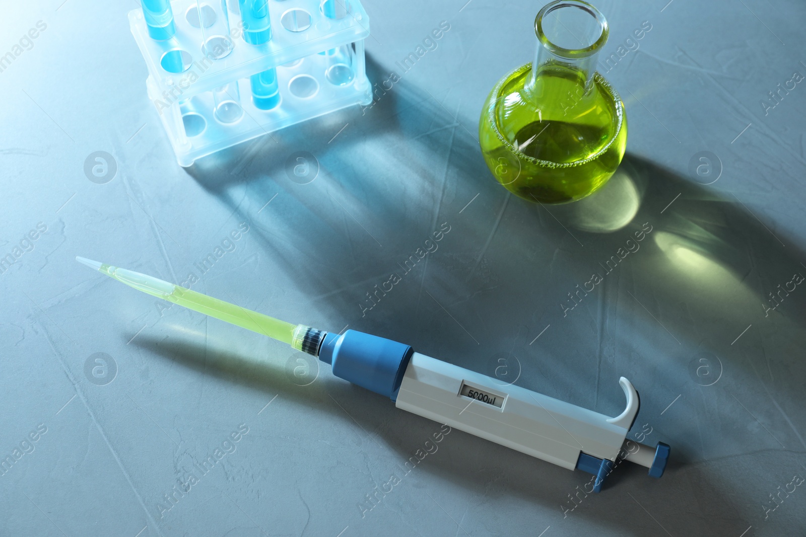 Photo of Laboratory analysis. Micropipette, flask and test tubes on grey table