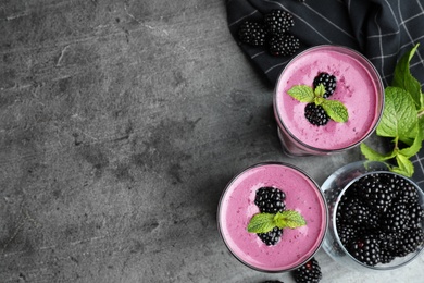 Photo of Glasses of tasty blackberry smoothie on grey table, flat lay. Space for text