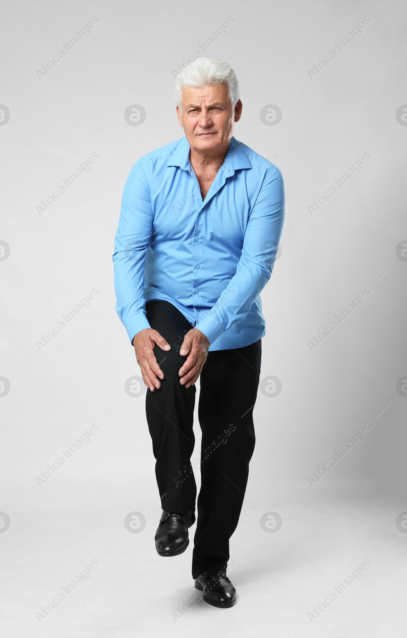 Photo of Full length portrait of senior man having knee problems on grey background