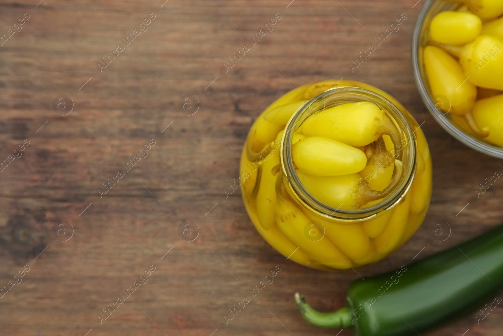 Photo of Fresh and pickled jalapeno peppers on wooden table, flat lay. Space for text