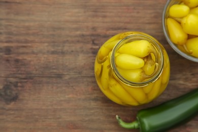 Fresh and pickled jalapeno peppers on wooden table, flat lay. Space for text