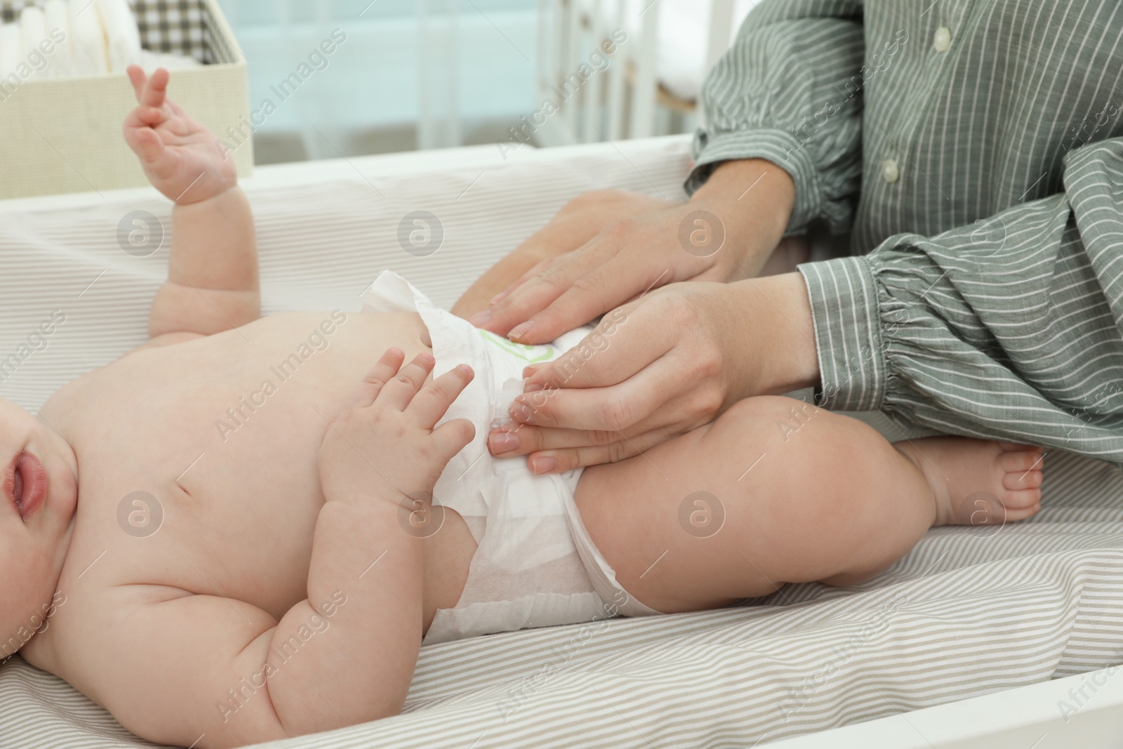 Photo of Mother changing baby's diaper on table at home, closeup