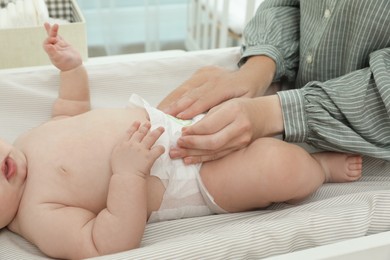 Mother changing baby's diaper on table at home, closeup