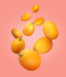 Delicious fresh kumquats falling on pink background