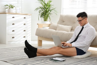 Photo of Businessman in shirt and underwear working on laptop at home