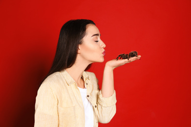 Photo of Woman holding striped knee tarantula on red background. Exotic pet