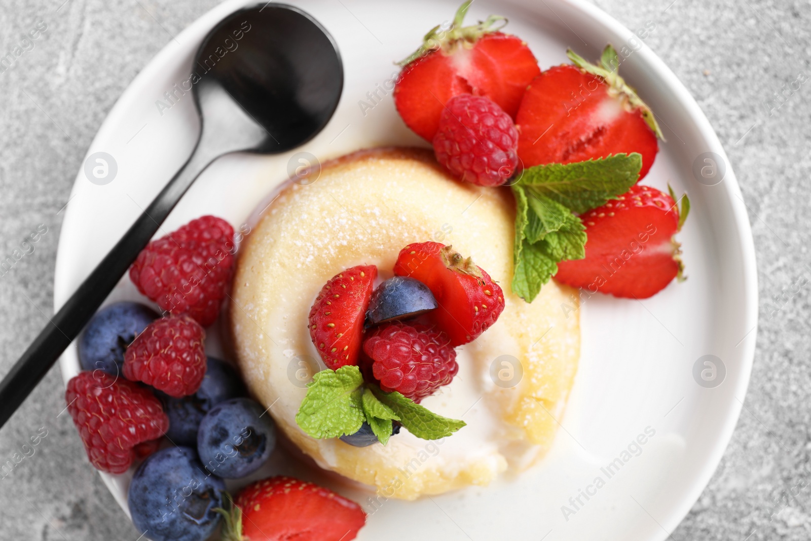 Photo of Delicious vanilla fondant served with fresh berries on grey textured table, top view