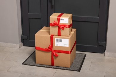 Photo of Christmas gift boxes on floor near door. Sending present by mail