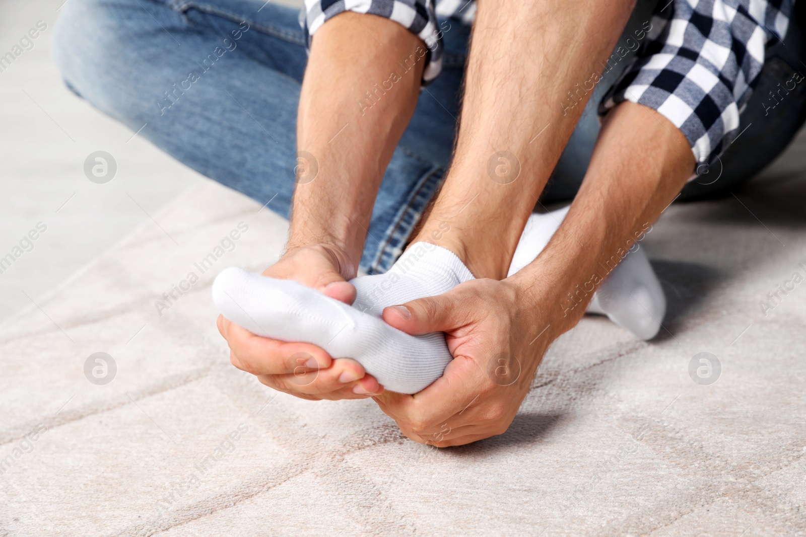 Photo of Man rubbing sore foot at home, closeup