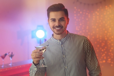 Young man with glass of martini cocktail at party